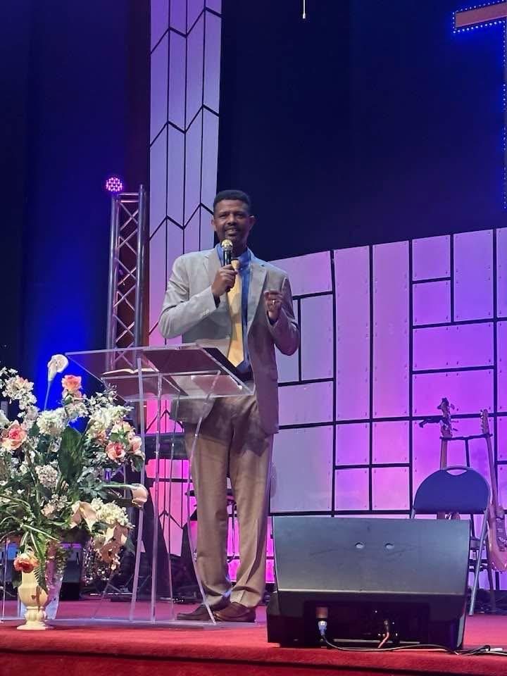 A speaker addressing a gathering from a church stage.