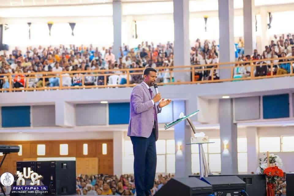A speaker addressing people gathered in a two-level church hall.